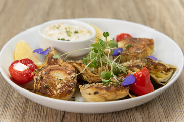 Hearty plate of artichoke hearts arranged on the plate and served with a creamy dipping sauce