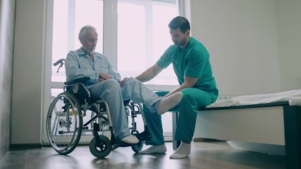 Professional physical therapist helping elderly man to do exercise, mobility