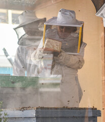 Little girl inside an apiary using the bee smoker. Selective focus. Concept of sustainable beekeeping.