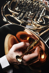 Obraz premium French horn player hands with mute close up. Brass music instrument