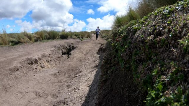A woman is walking and hiking on a trail of dirt on the moorlands of the Andes. A place with a dormant volcano called Rucu Pichincha near Quito, Ecuador.