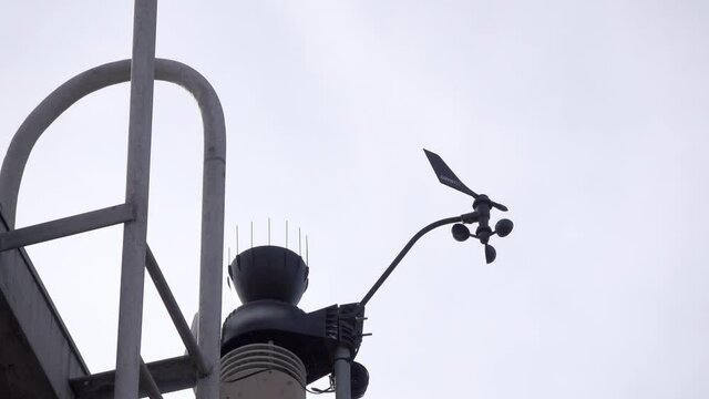 Anemometer spinning to measure wind speed.  Bird flies through shot.