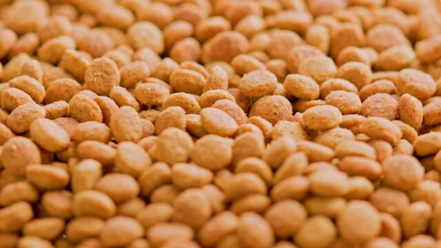 full frame loop rotating background of small dry orange cat food crockets