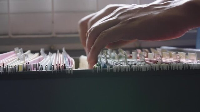 Close-up hand of businessman searching for financial and accounting file paperwork in an office file cabinet