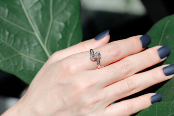 Heart diamonds ring on woman hand with leaf background