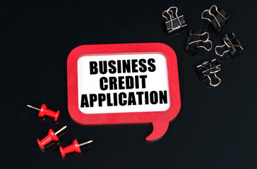 On a black surface, office supplies and a red plaque with the inscription - Business Credit...