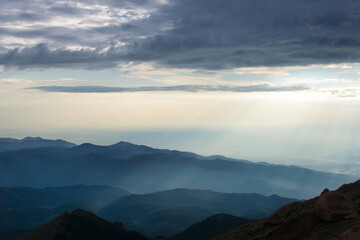 Obraz premium Sunrays over mountains with hazy clouds
