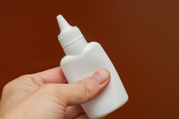 paper glue in a white tube in hand on a red background