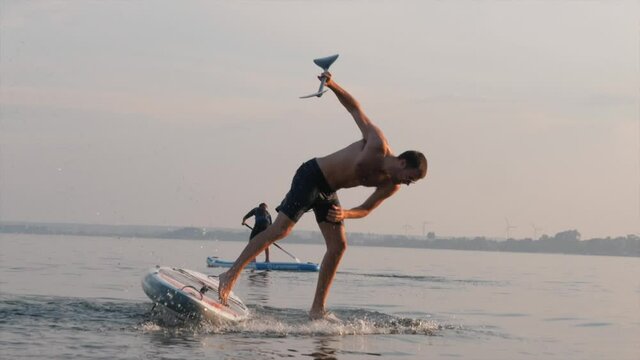 Man falling from a board into the sea during sunset