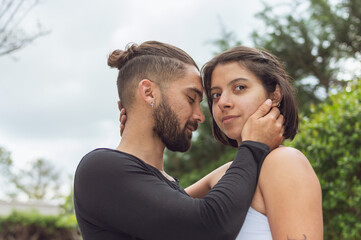 Obraz premium Young man in love touching his beloved's face with his eyes closed while she looks at the camera