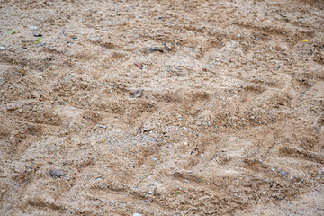 Tire print on gravel. Tractor tire shape on the ground. Offroad closeup. Grunge structure, abstract pattern. Selective focus on the stones, blurred background.