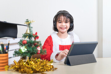 Asian children little girl dress Christmas Santa Claus chatting with friends on digital tablet. Christmas Holiday Concept Stock Photo