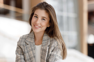 A woman is sitting in a shopping mall, laughing and smiling. Young blogger girl, close-up portrait...