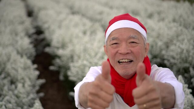 Cheerful happy thumbs up Asian senior man with red scraft and Christmas Santa Claus 