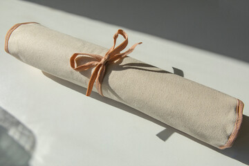 A parchment diploma scroll, rolled up with red ribbon laid at an oblique angle