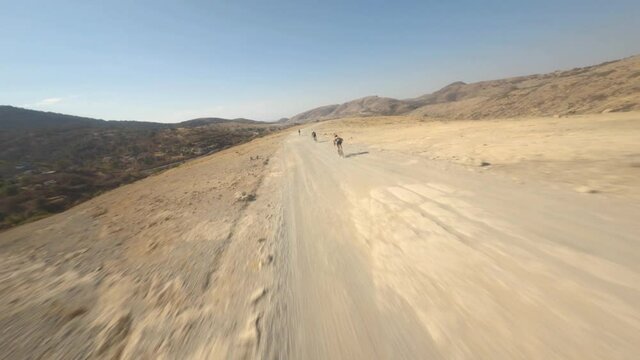 FPV shot weaving through a group of mountain bikers in the desert hills of Mexico.