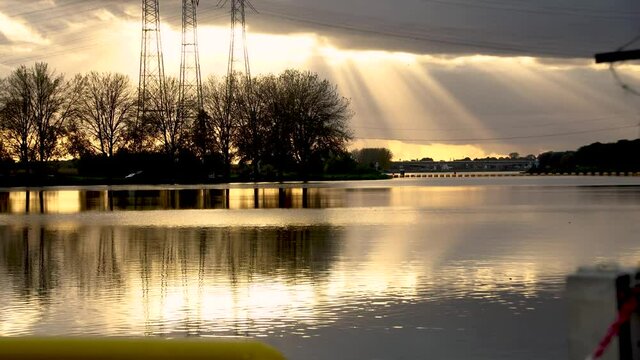 Sun rays over water surface and electric towers in Netherlands