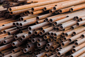 Many small-diameter metal pipes for gasification and construction lie in a stack in an open warehouse on the street. Solid industrial background for the supplier of metal pipes. New products.