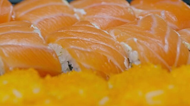 Japanese sushi rolls with Philadelphia cheese, covered with salmon slices. Japanese food. Close-up.