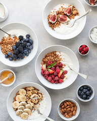Breakfast, granola with yogurt, berries, fruits and nuts on a light background, view from above