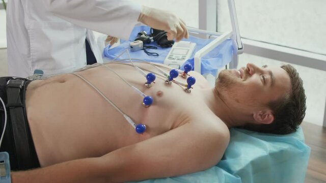 Electrocardiogram Procedure for Diagnosing Heart Disease. A Cardiologist Puts Electrodes on the Bare Chest of a Young Man Lying on the Couch To Take an Electrocardiogram in the Clinic'S Office.