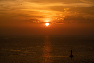 Fototapeta premium Sunset on the sea and through the clouds over. Tranquil seascape with the horizonal skyline.