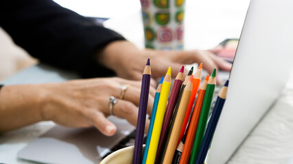 Unrecognizable woman working on a laptop, at home, with colors in the foreground.