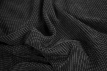 Black corduroy. Soft wavy folds of fabric. Elegant background with copy space for design.