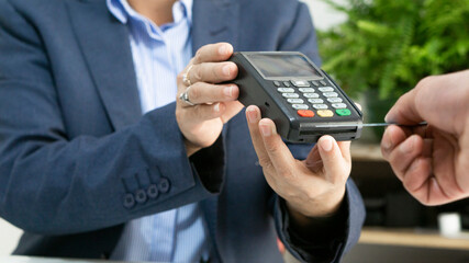Unrecognizable person paying at a bank terminal. Business.