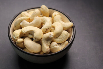 Tasty Cashew nuts in a mini wooden basket on the back background. Goan Kaju. Copy space. Dry fruits background or festivals banners. Diwali gift concept.
