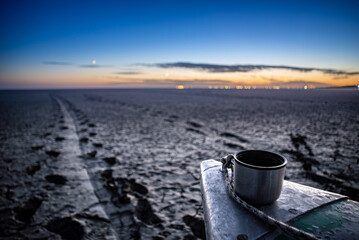 A cup of coffee on a boat at the bottom of a dried up sea