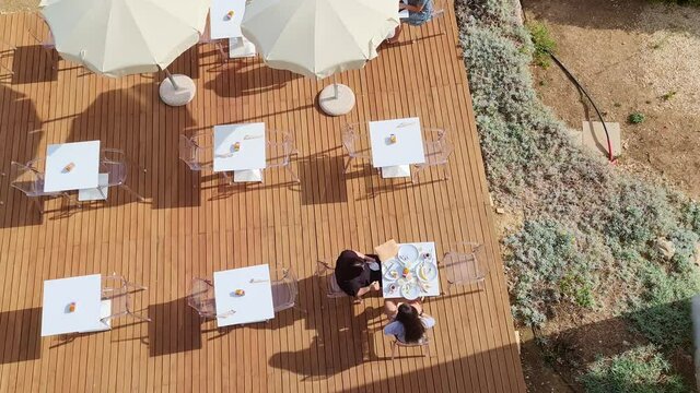 Couple of women enjoys outdoor breakfast. Overhead aerial view