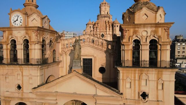 Aerial close up shot overlooking at statue of Christ on the cathedral roof, pull out reveals the whole church building exterior, at Cordoba, Argentina.