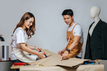 Young couple fashion designers make paper pattern in studio