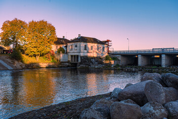 A reflection of autumn trees in the river water. Hydro-electric station.