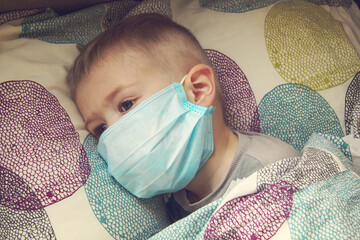 Kid using the medical face mask . Protection against corona virus. Sick child breathes through a...