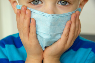 Kid using the medical face mask . Protection against corona virus. Sick child breathes through a...