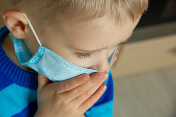 Kid using the medical face mask . Protection against corona virus. Sick child breathes through a...