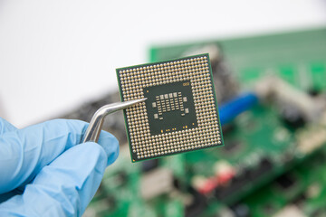 Hand in a blue glove holds tweezers with pcb chip assembly on pcb backround on the production of...