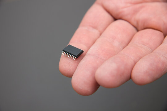 Hand holds chip compenent. Embedding the chip under human skin, microcontroller implanting NFC technology