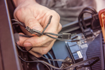 Assembling a personal desktop computer. Connecting power supply, hard ware and motherboard with a cable. Selective focus