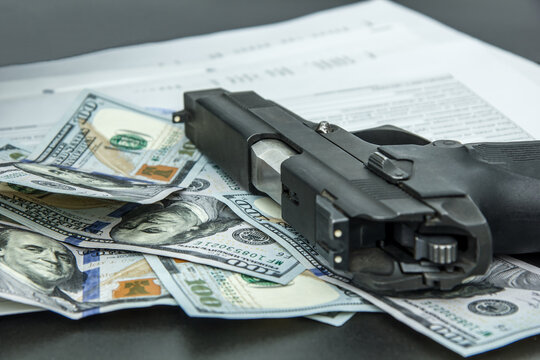 Corruption concept, with gun, bill and dollars placed on black desk.