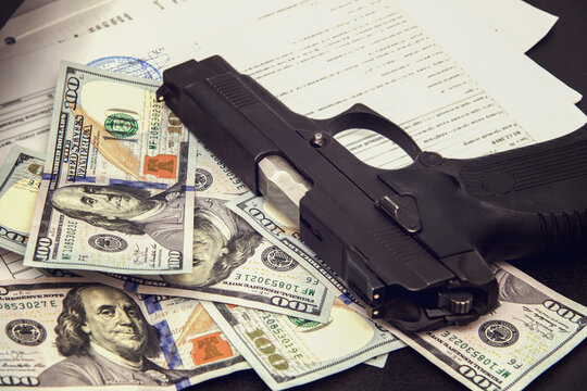 Pistol, money and documents on the office desk. The concept of blackmail, threats, murder for enrichment