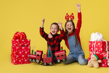 Children with gifts on a yellow background for the Christmas holidays