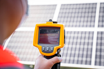 The technician takes the Thermoscan(thermal image camera) scan to the solar panel to check the hot...