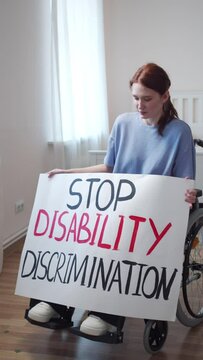 A disabled young woman is showing a poster and talking to the camera