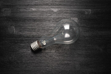 Old light bulb on the black wooden table flat lay background.