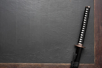 Katana sword on the old black wooden table flat lay background with copy space.