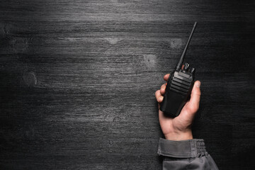 A worker with a walkie talkie radio station in the hand on the black flat lay background with copy...