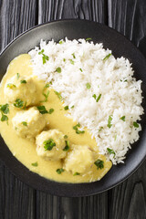 Danish Meatballs In Curry Boller i Karry close up in the plate on the table. Vertical top view from above